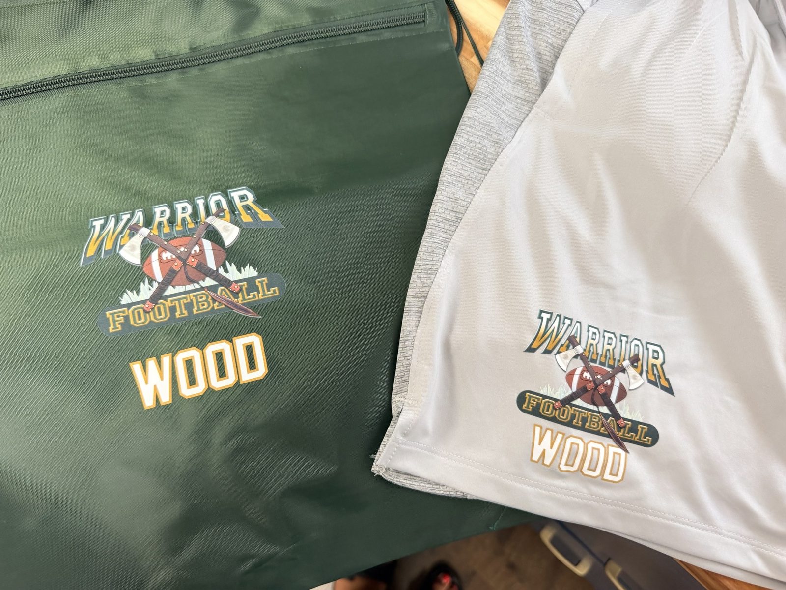 Green team duffel bag and grey shorts, both printed with a Warrior Football crest and a player's last name